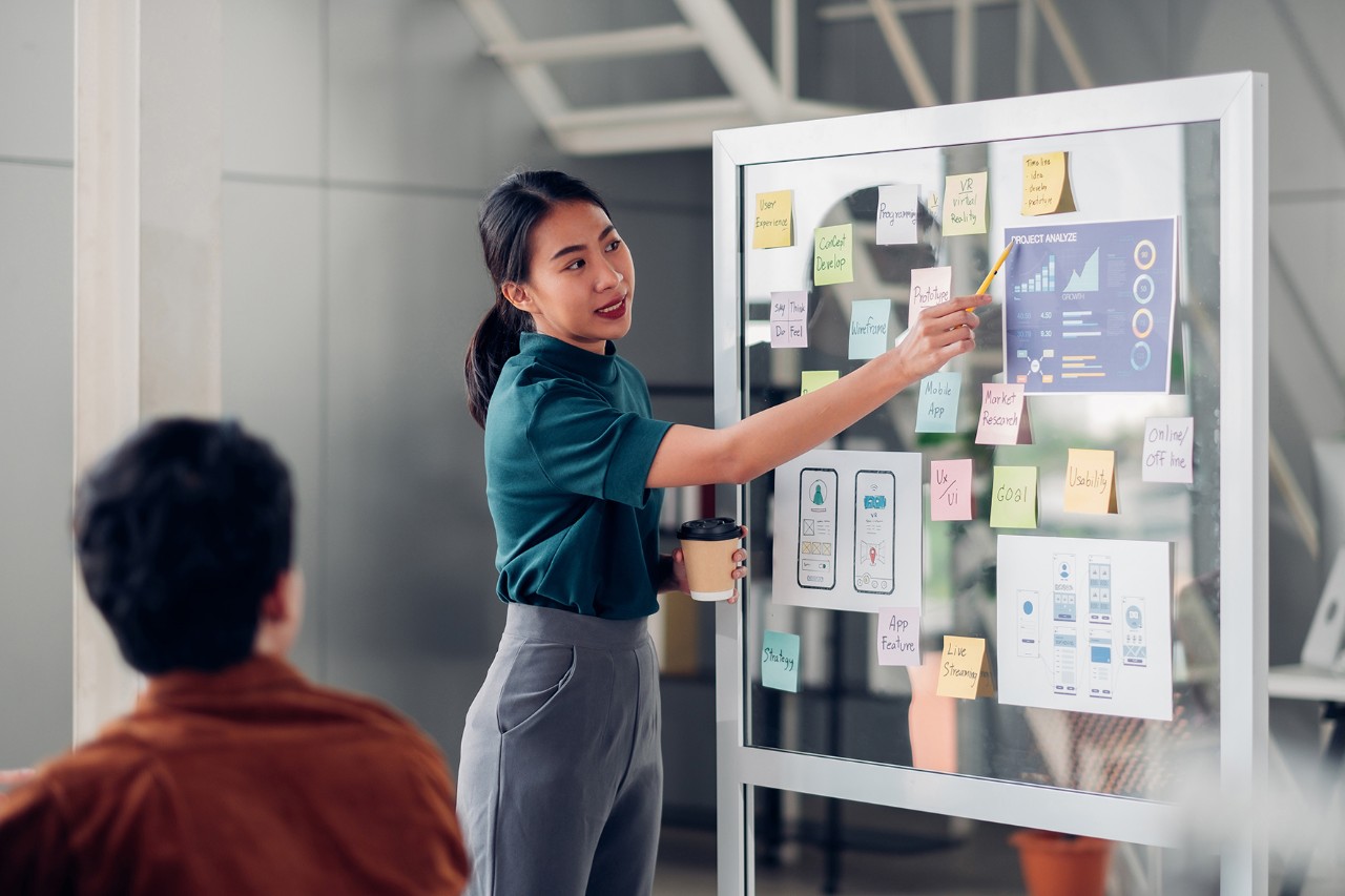 asian ux developer and ui designer presenting mobile app interface design on whiteboard in meeting at modern office.Creative digital development mobile app agency.digital transformation