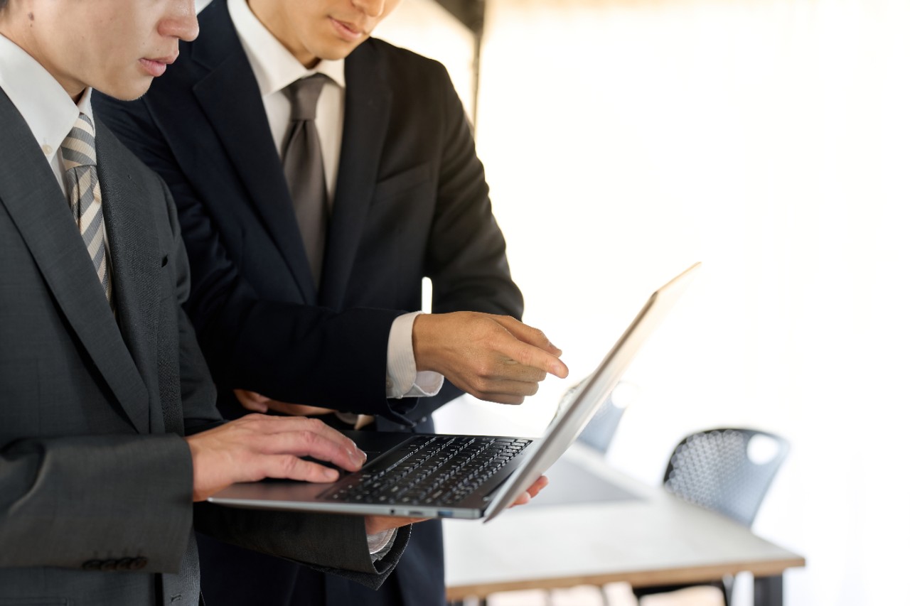 Businessman showing something on his laptop to another man
