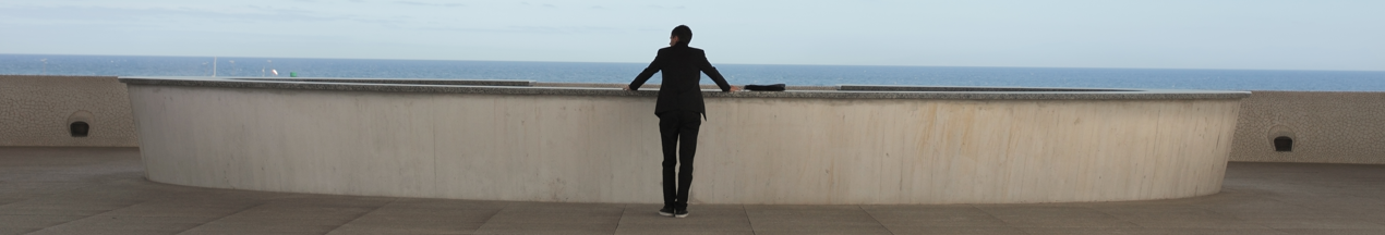 Man looking at the beach from a balcony 