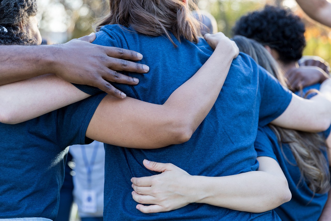 Rear view of unified diverse neighbors huddled up after cleaning up their neighborhood.