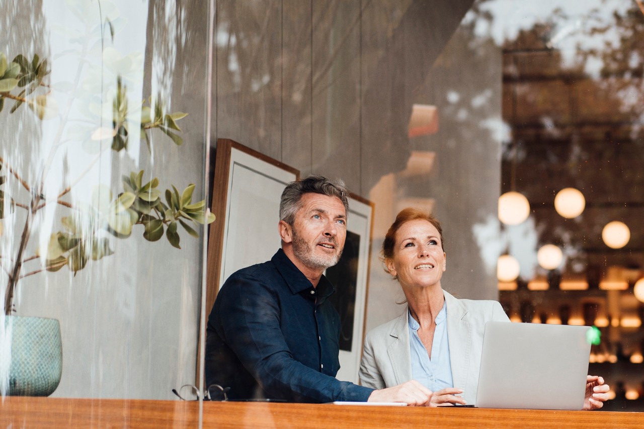 Businessman with businesswoman in cafe seen through glass window